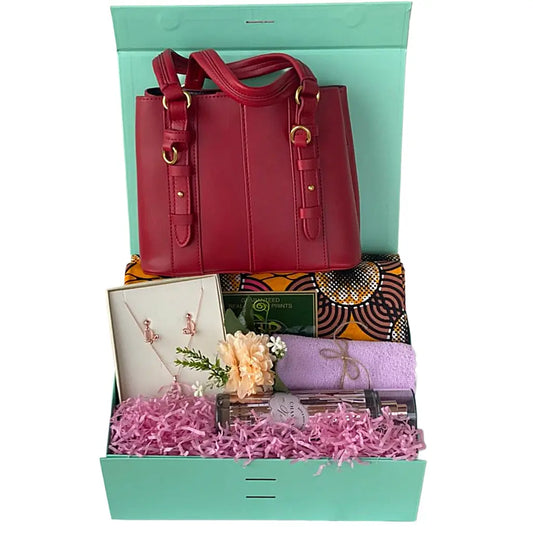 Red handbag in a gift box with pink flowers and other items.
