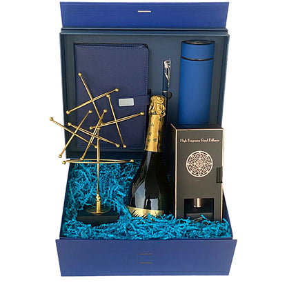 Gift set with a bottle of champagne, blue tumbler, gold stand, and blue box on a white background