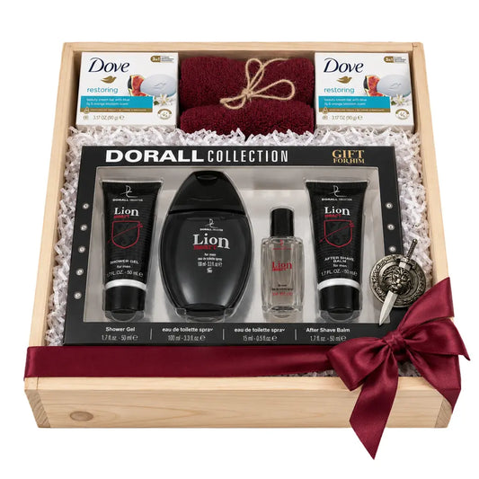 A wooden gift box containing a Dorall Collection men's grooming set, including a black shower gel tube, toner bottle, shave balm tube, a small clear fragrance bottle, a folded burgundy towel, two boxes of Dove body wash, and a decorative medallion, arranged on white paper filler with a burgundy ribbon.