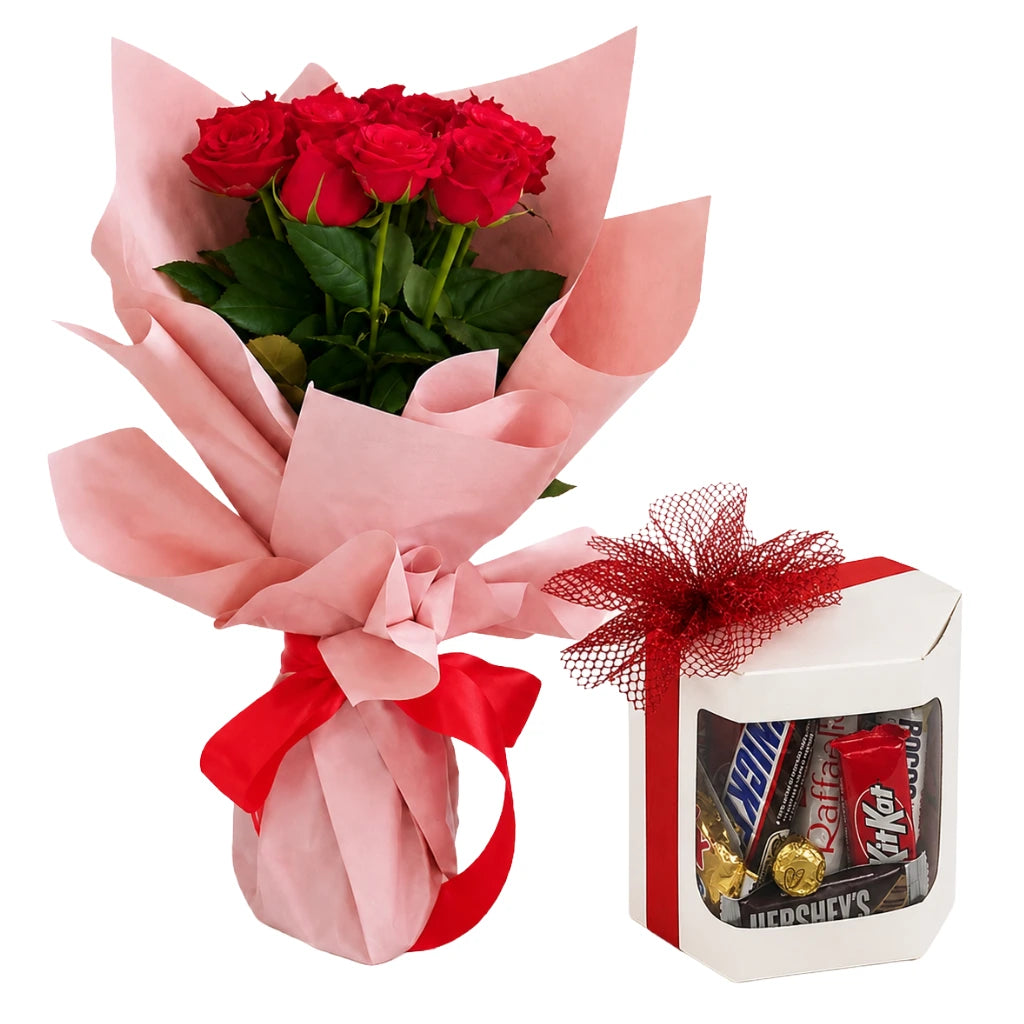 A gift set featuring a bouquet of six red roses wrapped in pink paper with a red ribbon, alongside a white gift box filled with assorted chocolates and wrapped candies, tied with a red mesh bow.