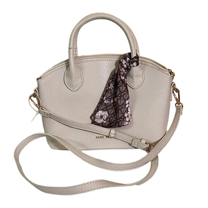 Beige handbag with a floral scarf attached on a white background