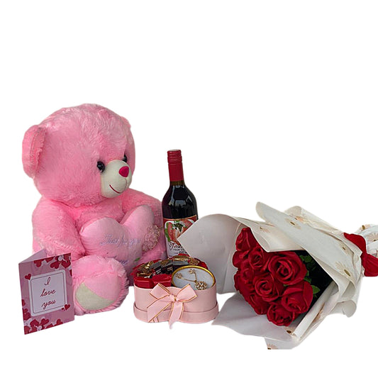 Pink teddy bear, bottle of wine, red roses, and small gift box on a white background