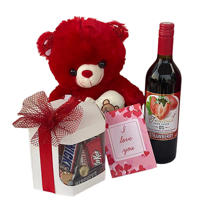 Red teddy bear with a gift, small bag, and bottle of strawberry-flavored wine on a white background