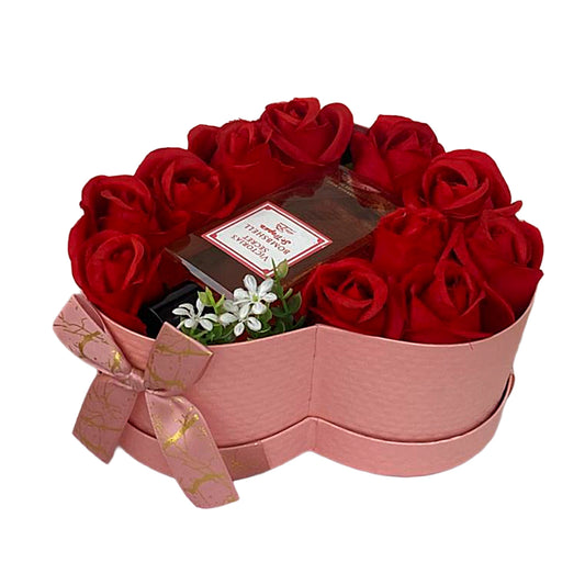 Heart-shaped box with red roses and a small plant on a white background
