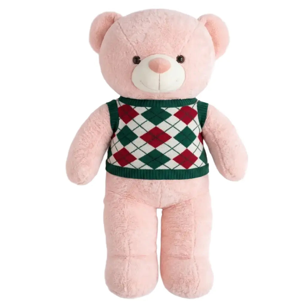 A pink plush teddy bear wearing a green, red, and white argyle sweater vest, set against a plain white background.