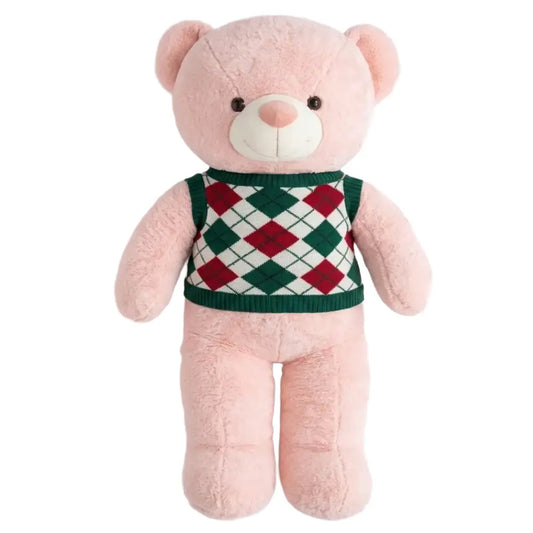 A pink plush teddy bear wearing a green, red, and white argyle sweater vest, set against a plain white background.
