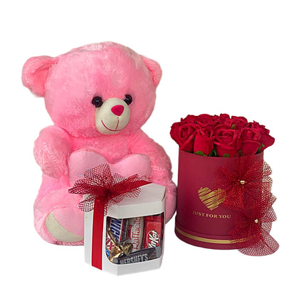 Pink teddy bear, red roses in a box, and a small gift set on a white background