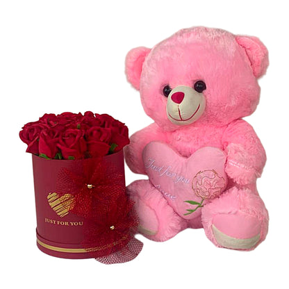 Pink teddy bear with a heart and red roses in a box on a white background