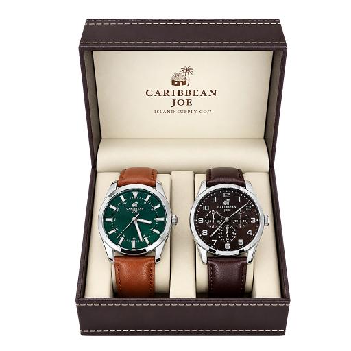 A boxed pair of wristwatches from Caribbean Joe Island Supply Co. The open dark brown presentation box with cream interior holds two watches: one with a green dial and brown leather strap, and one with a black dial and dark brown leather strap.